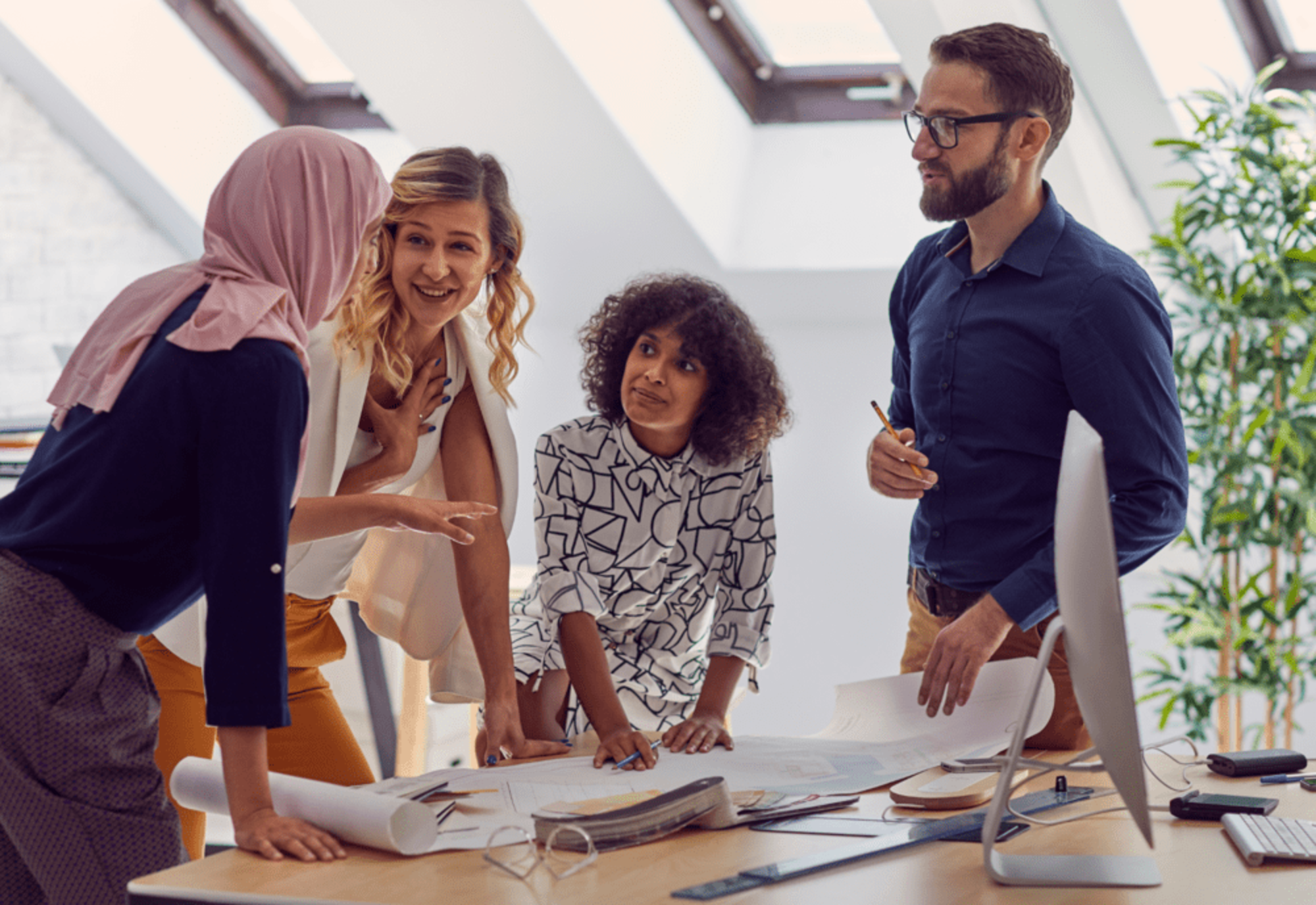 A group of people stood around a desk having a discussion